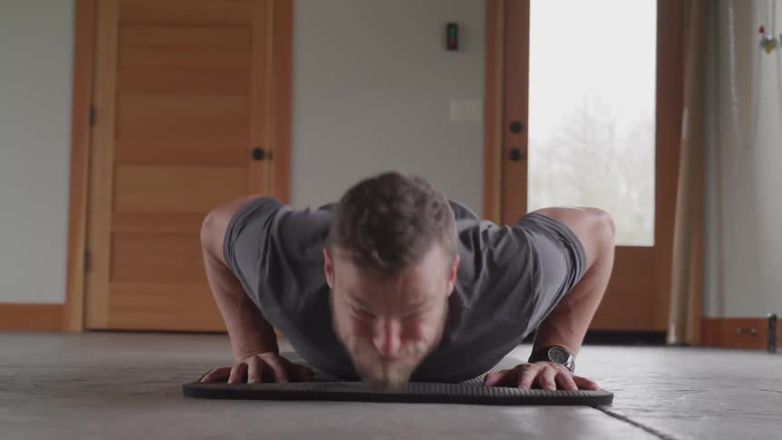 Man doing push ups on mat in house