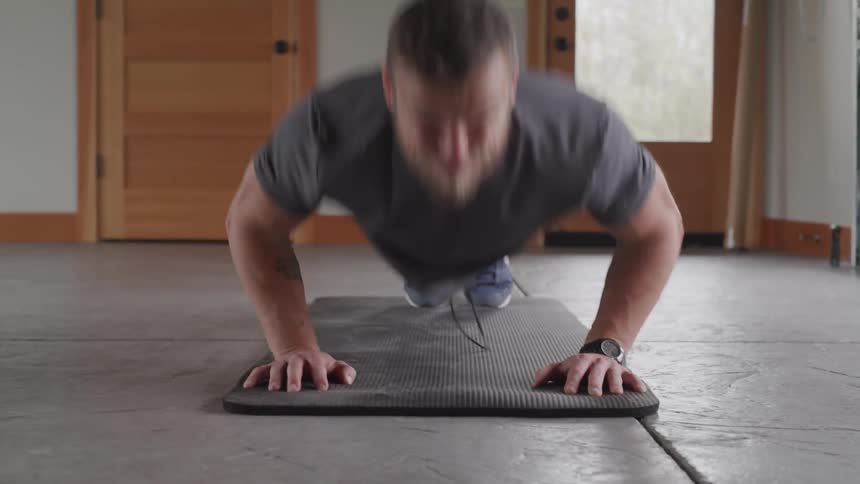 Man doing push ups on a mat in a room