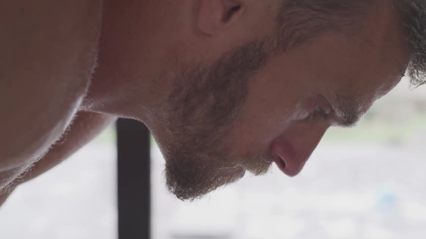 Blonde bearded man takes deep breaths during workout in the daytime