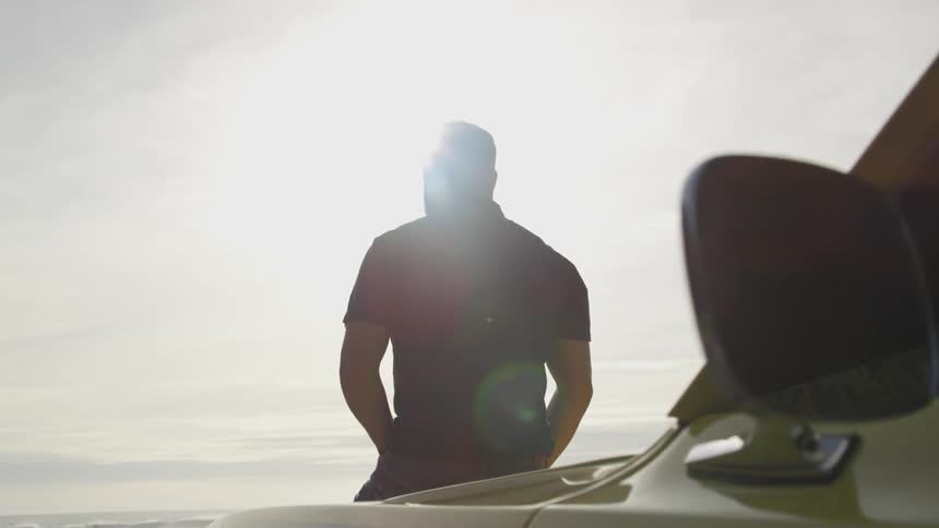 A man leans on the hood of a vehicle