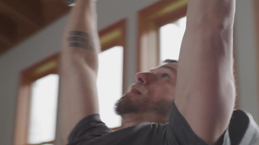 A man lifts barbells in a gym