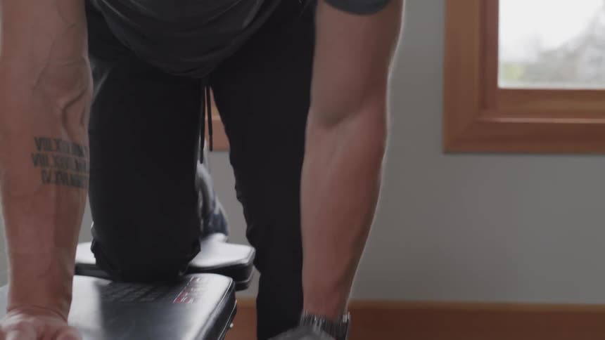 A man exercising with a dumbbell on an exercise bench