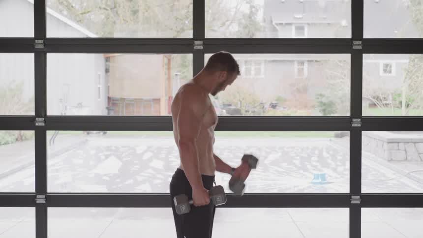A topless white man lifts dumbbells