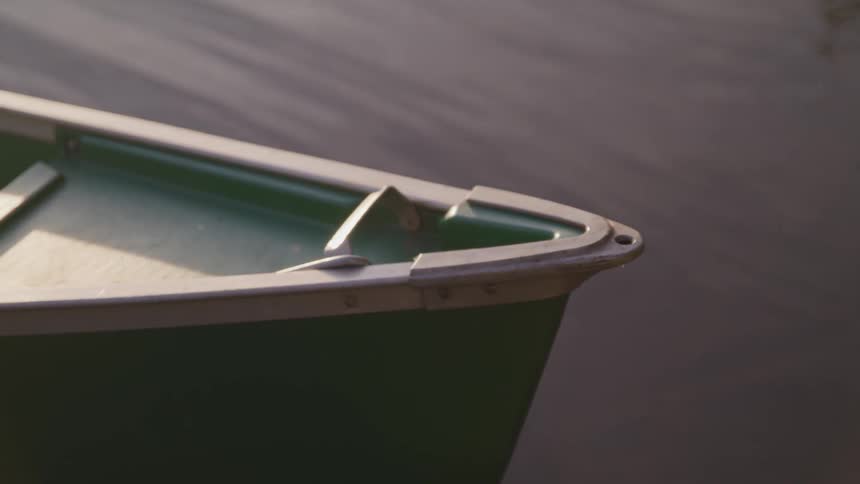 A green canoe sitting in calm water