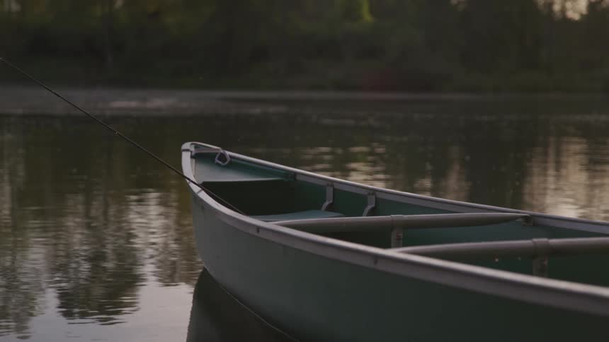 Boat with fishing rod floating on a calm lake