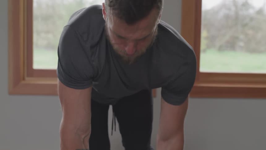 A man lifts weights with his left arm while kneeling on a bench