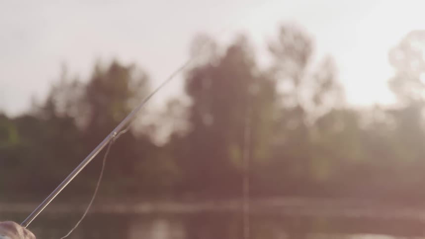 Man holds on to a fishing pole as he fishes in a lake