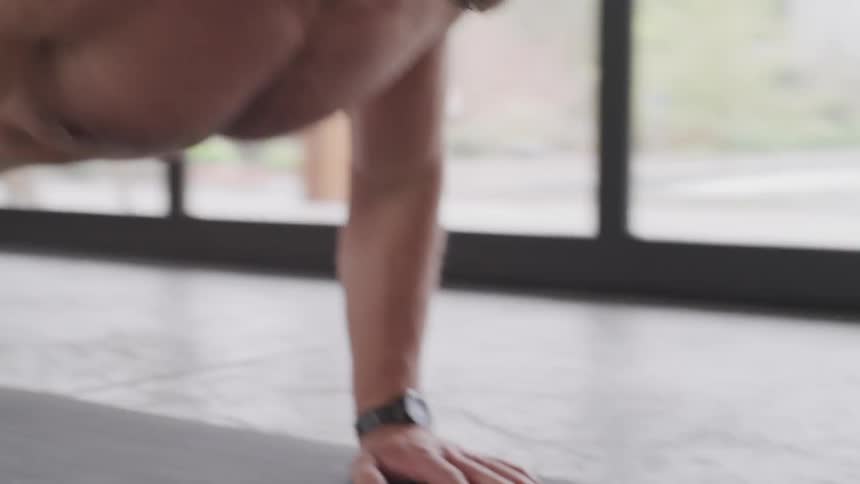 A man on a mat in an indoor gym doing push ups