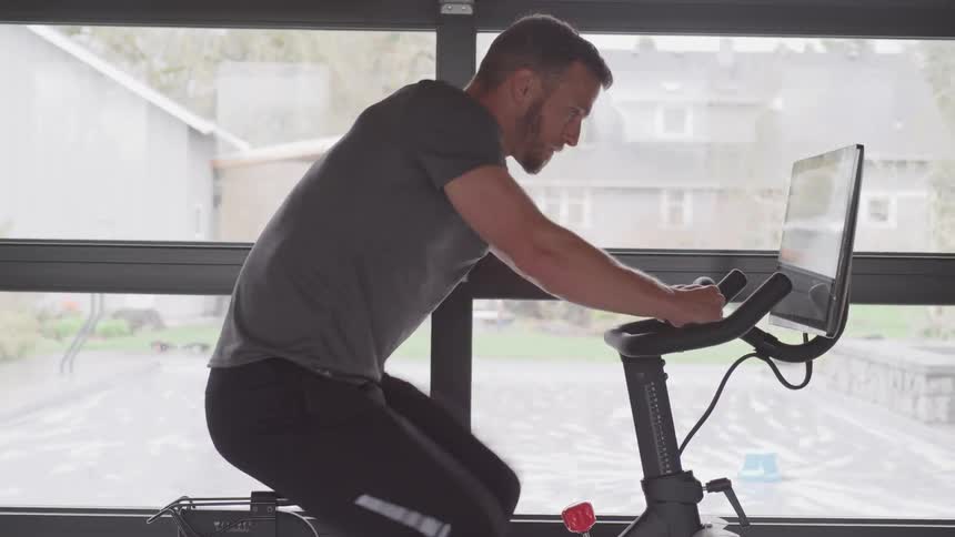 Man pedals on exercise bike while watching monitor