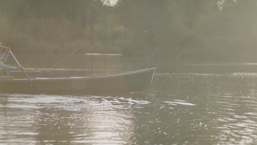 A man rows a boat with a fishing line in the water