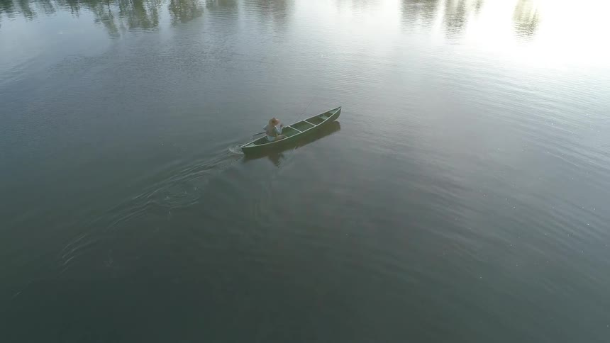 A person rows a canoe on a calm lake