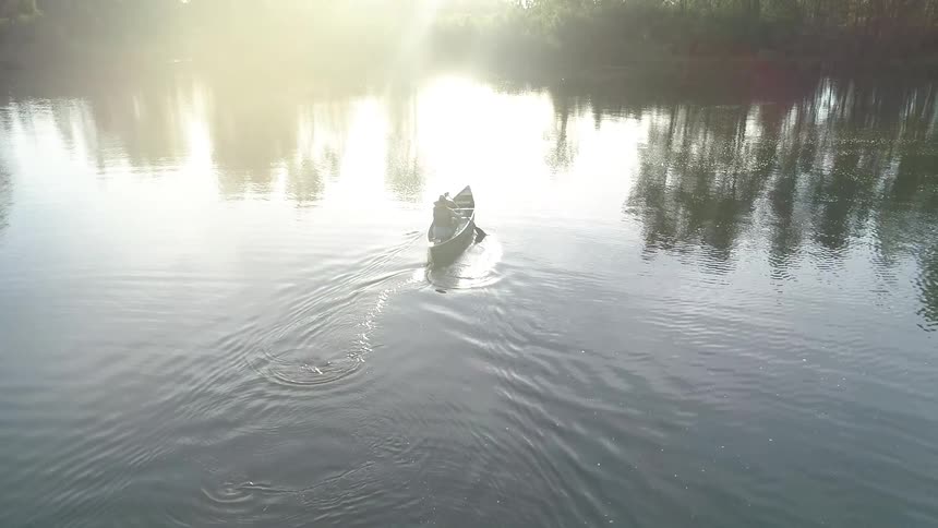 A person is rowing a canoe outdoors on a lake