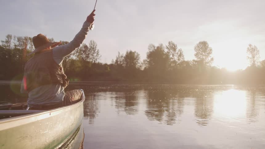 A man casts his fishing line into the lake from his boat