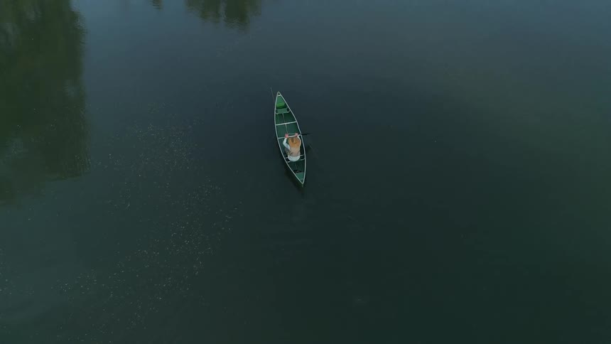 An aerial view of a person rowing a boat in a body of water