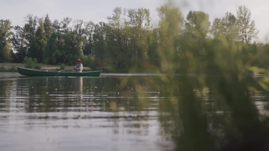 A man casts a fishing rod as he sits in a boat