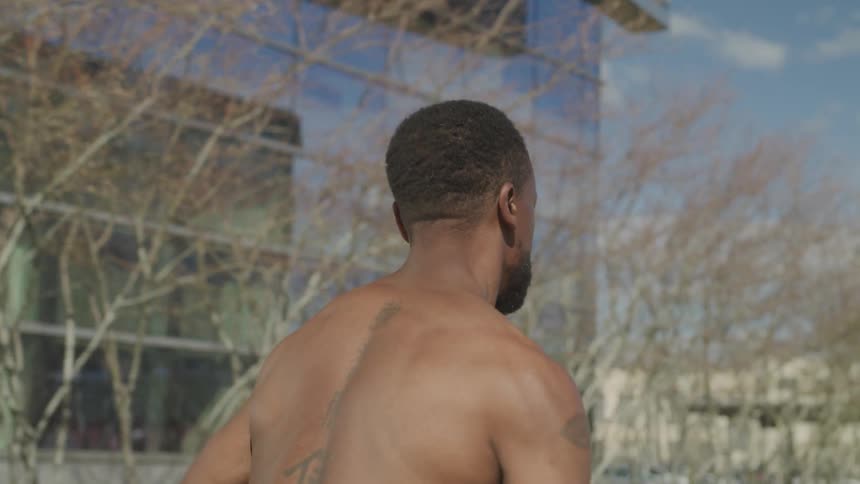 Shirtless man runs down the street near the buildings