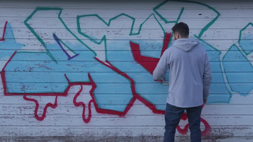 A man is painting graffiti on a wall