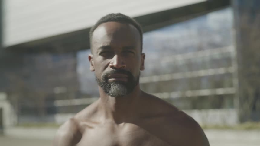 A buffed black man walking towards the camera