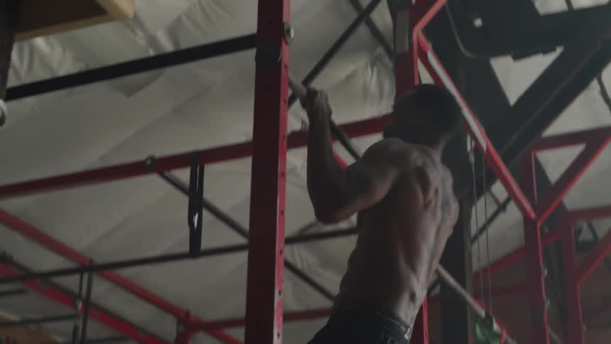 A man doing pull ups in an indoor gym