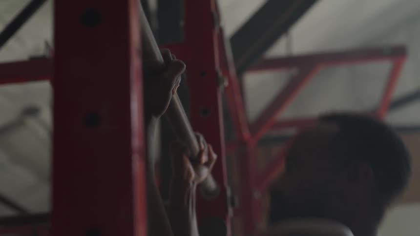 A man doing pull ups in an indoor gym