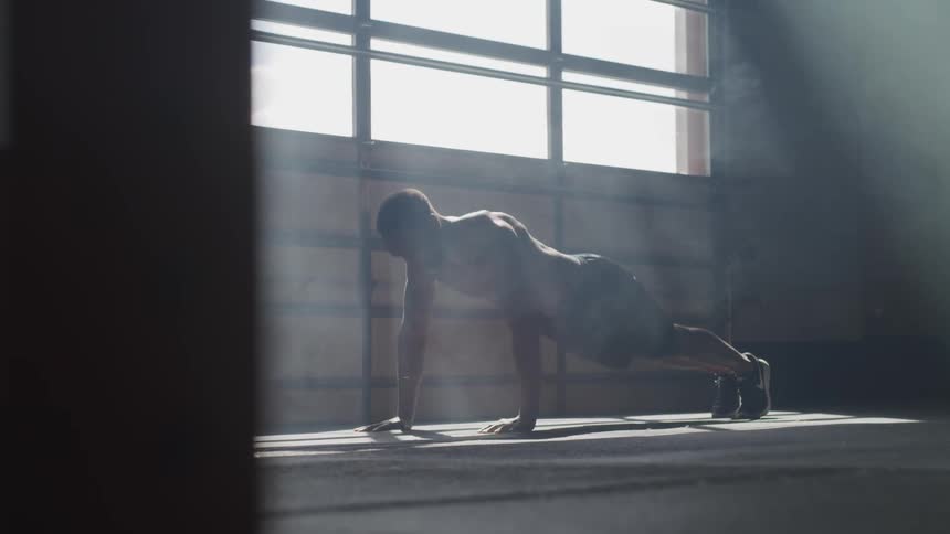 Silhouette of a man doing push ups neat a window in a building