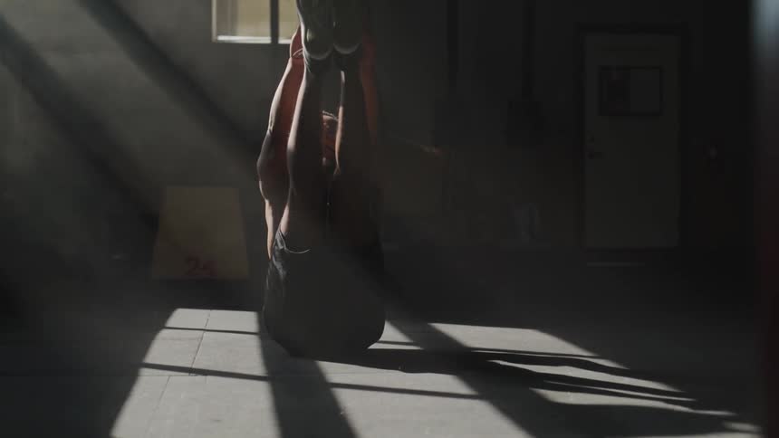 Shirtless black man does abs workout on the ground while the sun streams through the window