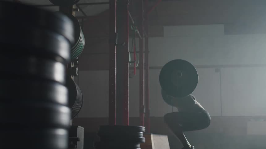 A shirtless male is doing squats with heavy weights on his shoulders in a gym