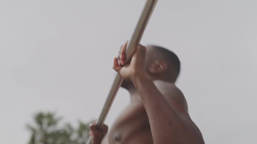 Black man doing pull up on the steel bar at the park
