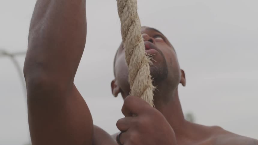 A man is climbing a rope outdoors