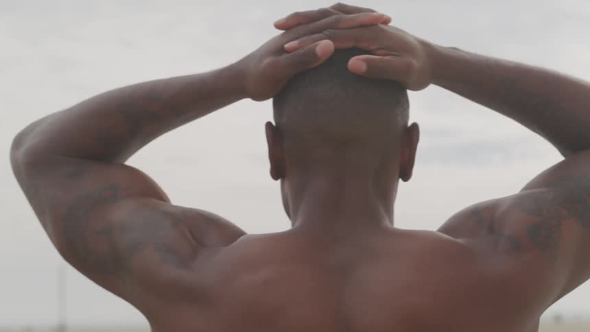 Man stands with hands on head on beach