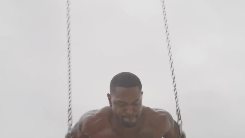 Man works out on rings on public beach
