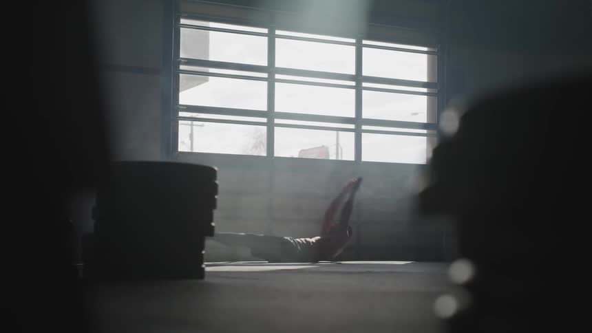 Man exercises near window in darkened gym