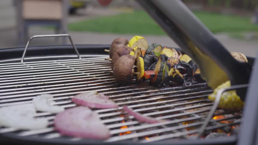 A person is grilling vegetables on a grill