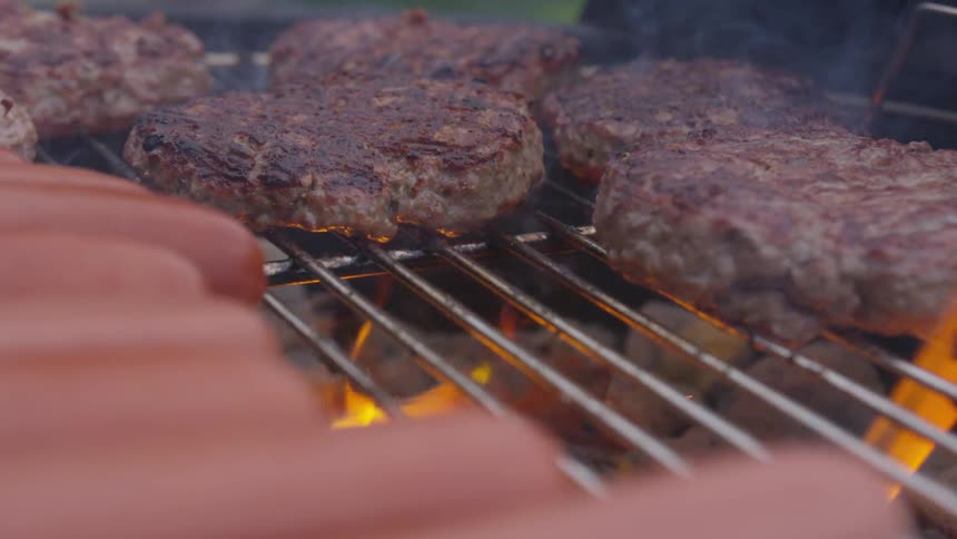 Hamburgers cook on a open grill
