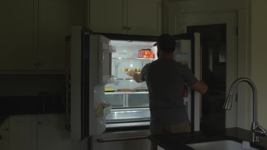 A man pulls a plate of food out of the fridge