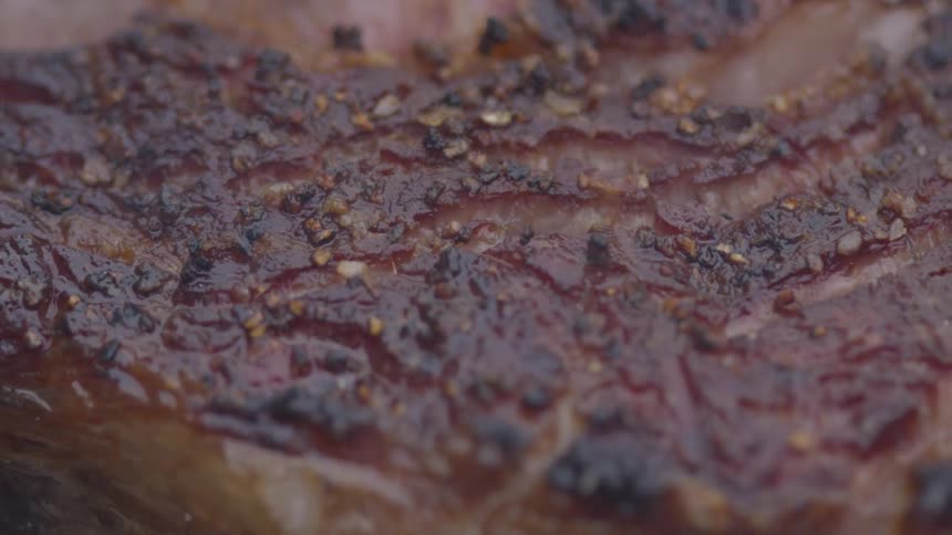 Cooked beef on a grill with flames underneath