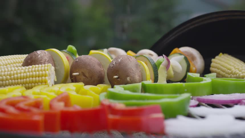 A person splashes salt onto food cooking on a grill