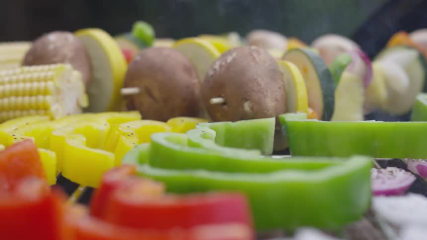 Kabobs and vegetables are cooking on a grill