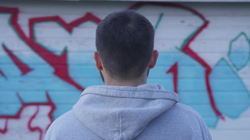 Man staring at the wall covered in paint