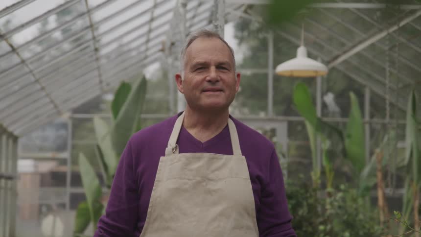 A man standing in a greenhouse with a large smile