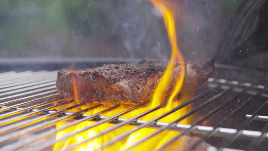 Flames flaring on a steak being grilled on a bbq