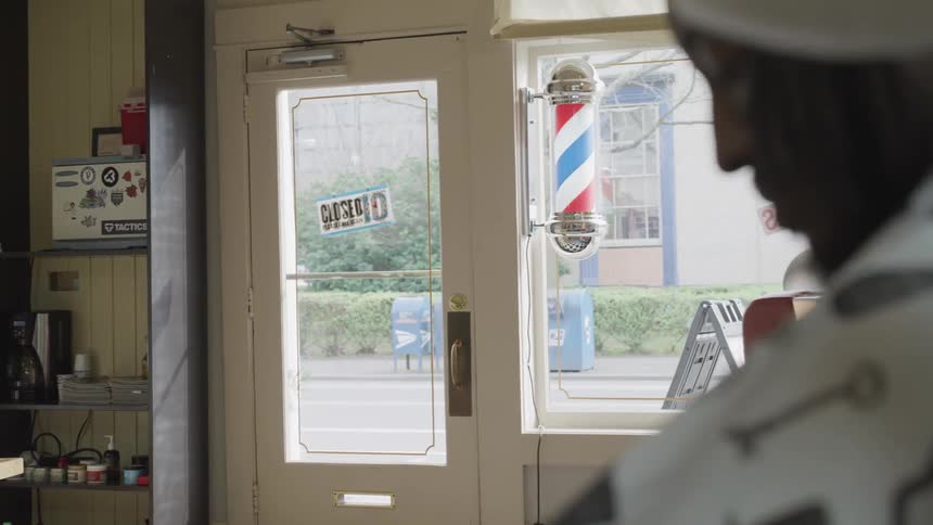 A man is getting his hair cut in a barbershop on a sunny day