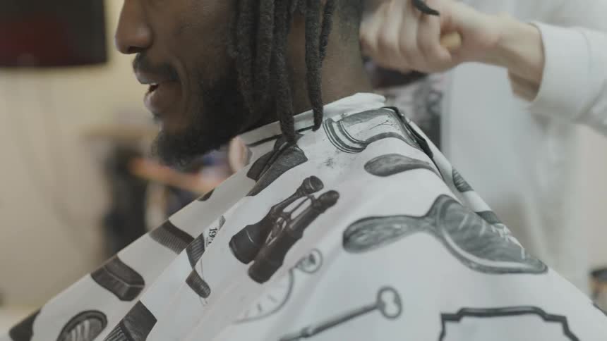 A black guy hairs is being shaved by barber