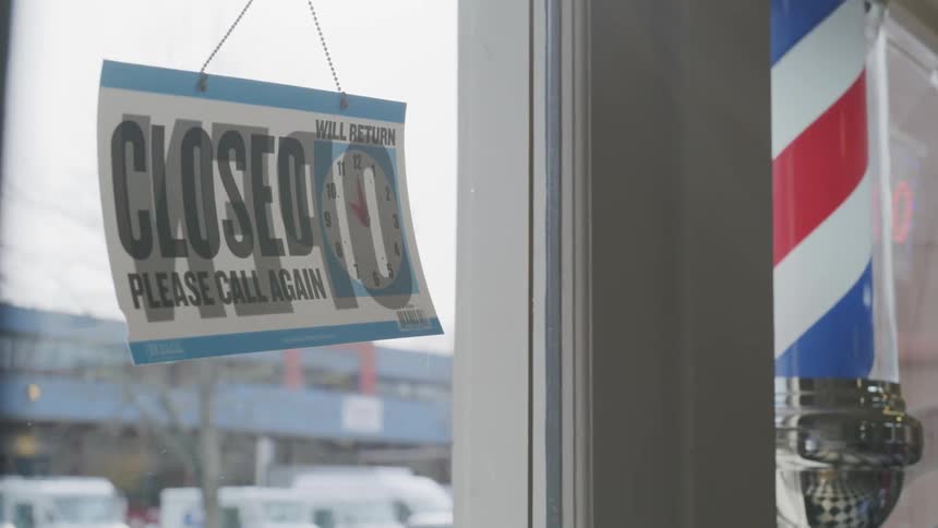 A glass window and door showing a barbershop pole and an open sign