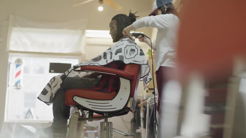 A white woman shaves a black mans neck