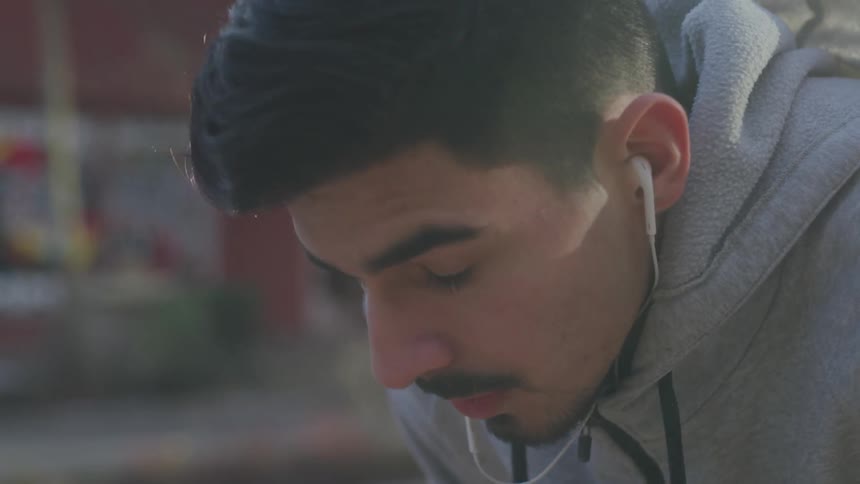 Man who wears earphones looks ahead in the city during daylight