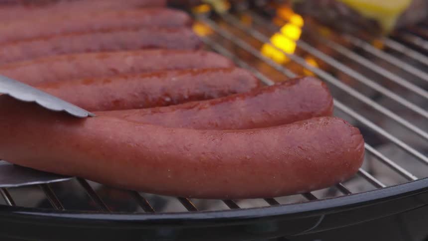 Hot dogs are being cooked on a grill