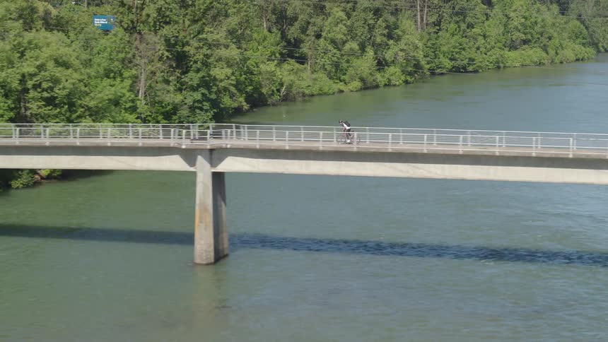 A bike rider crosses a long bridge