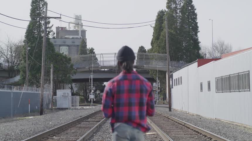 A man stands between two sets of railroad tracks