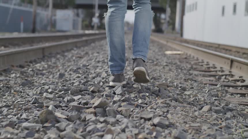 Male walking next to train tracks